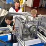 Das Förderband wird in PHYSICS FOR STORAGE & FOOD optimiert. Projektleiter Florian Wald schaut den beiden Software-Experten über die Schulter.